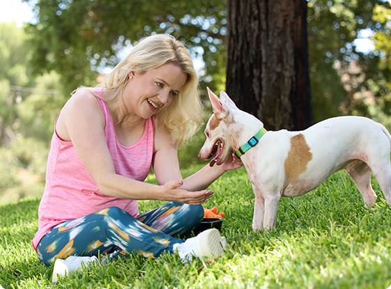 Kristina sitting on the grass outdoors with her dog