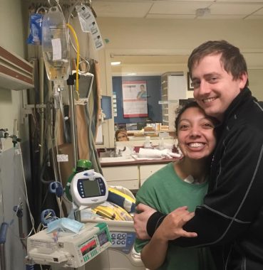 relationships and CF | Cystic Fibrosis News Today | Nicole and Jared smile and hug one another in a hospital room full of monitors and IV bags.