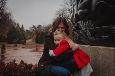 CF diagnosis | Cystic Fibrosis News Today | Jamie Rudnycky and her daughter, Louisa, pose in a forested area. Louisa is wearing a bright red coat.
