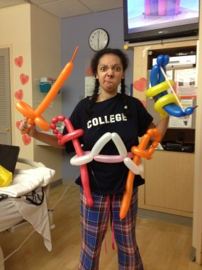 finding joy in chronic illness | Cystic Fibrosis News Today | Nicole wears a T-shirt and flannel pajama pants and poses with multiple balloon swords in a hospital room