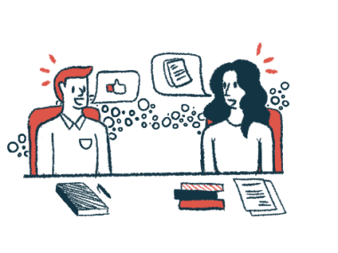 Two people sitting next to each other at a table talk to one another.