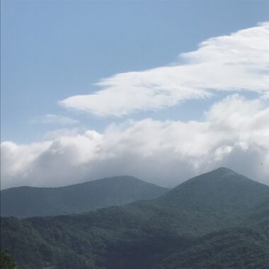 The peaks of a couple of mountains rise up into the clouds.