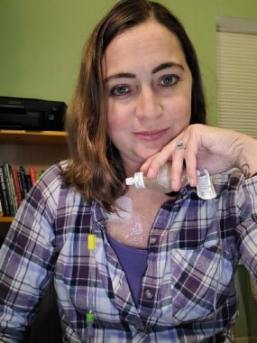 A woman is shown administering intravenous medicine through a port-a-cath.