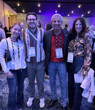 Four adults inside a convention setting stand together for a photograph.
